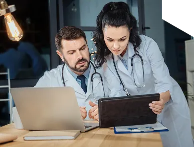 Two healthcare professionals reviewing payment information on a laptop and tablet